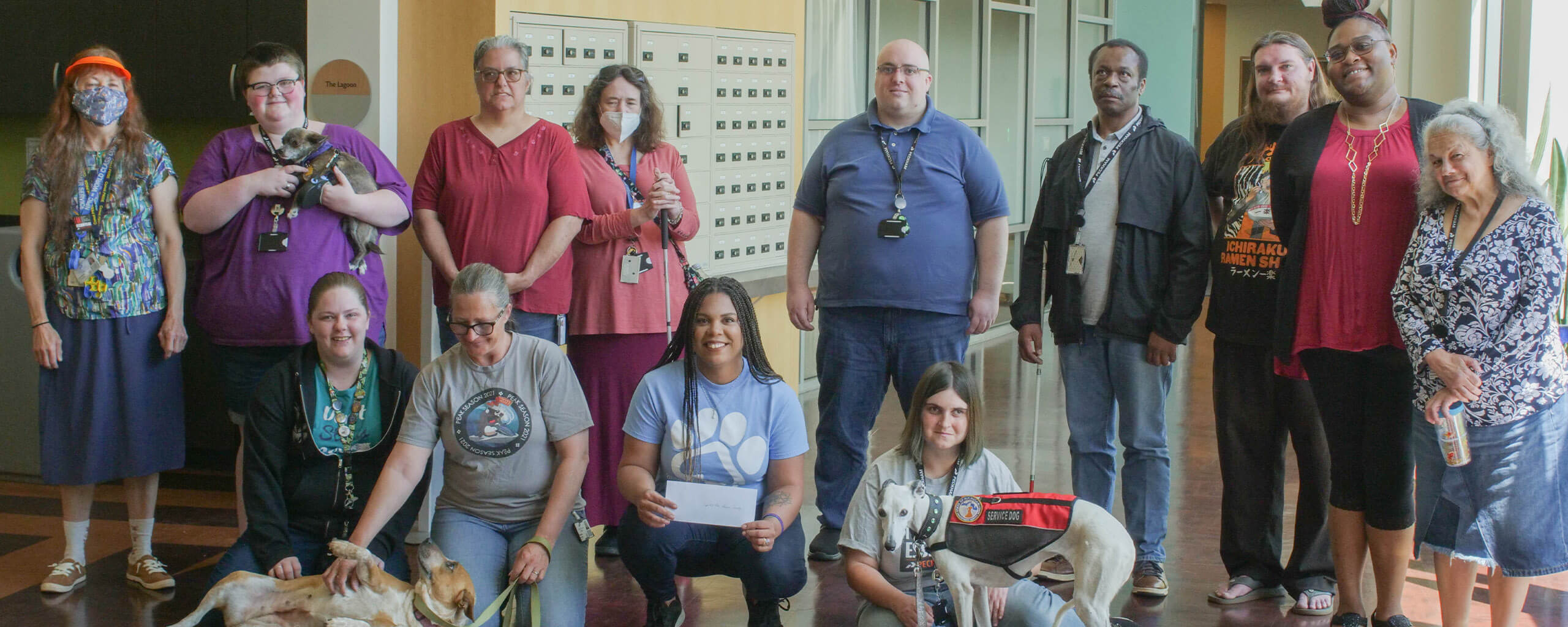 group of 13 people smiling with three service dogs