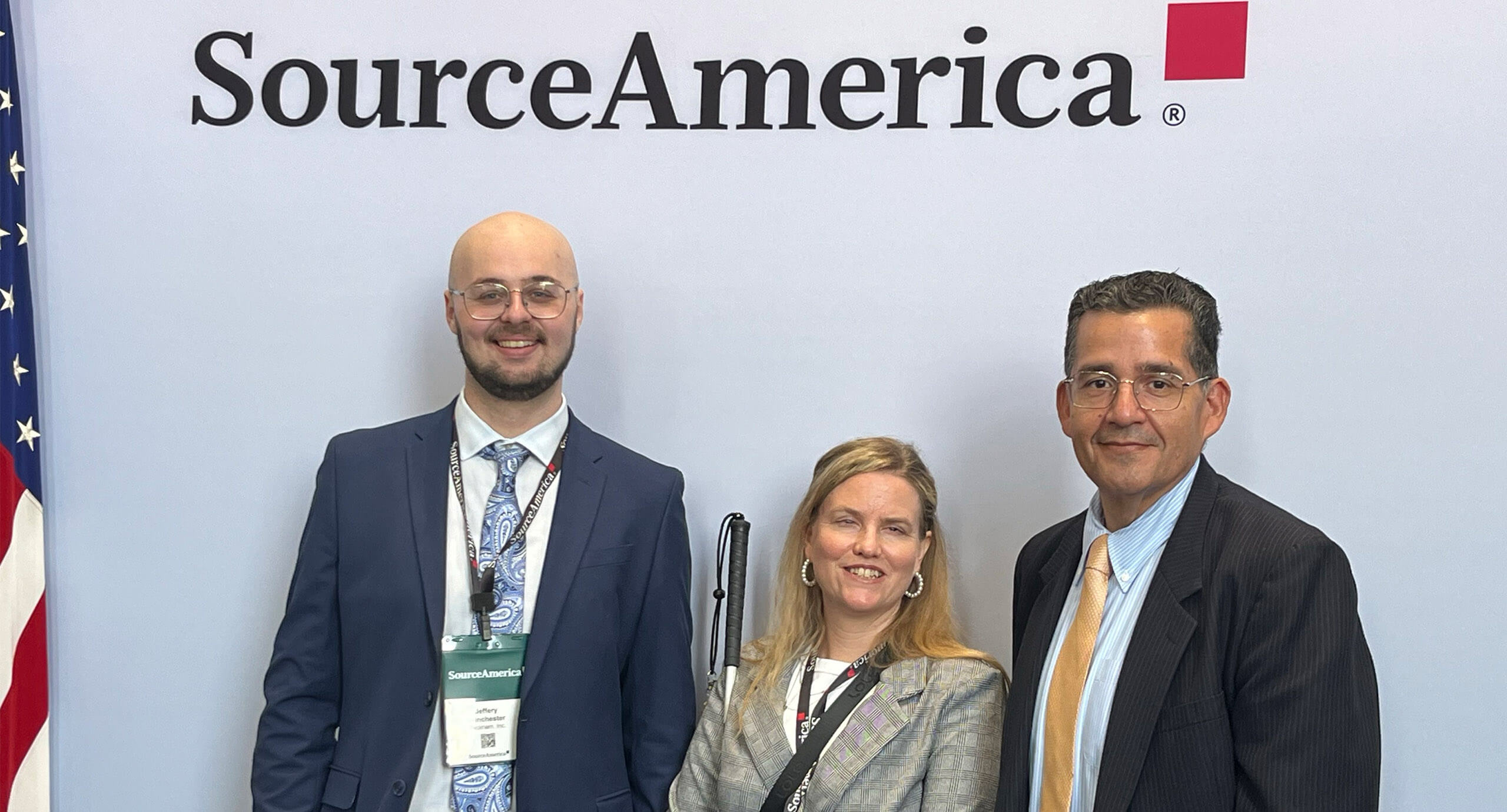 3 coworkers in front of a SourceAmerica logo on a wall