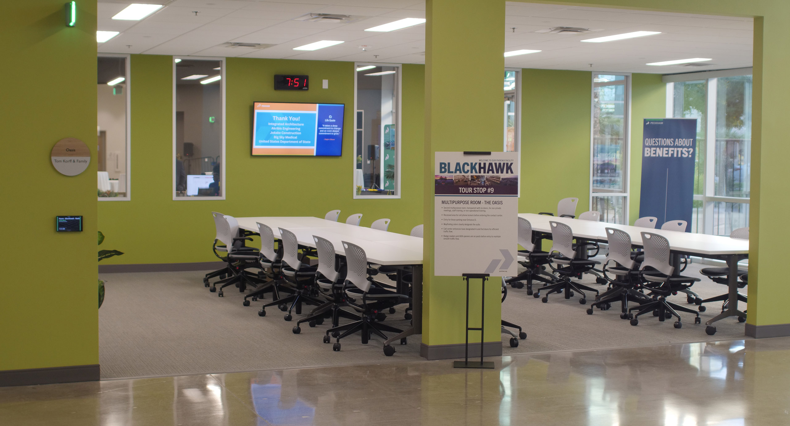 Meeting room featuring two tables and a screen for presentations