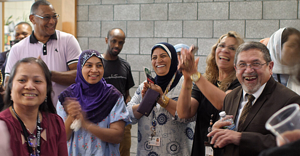Ten people gathered smiling and clapping.